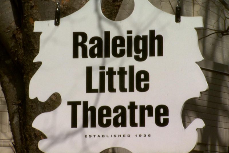a white sign reading “Raleigh Little Theatre, Established 1936” hanging outside. 
