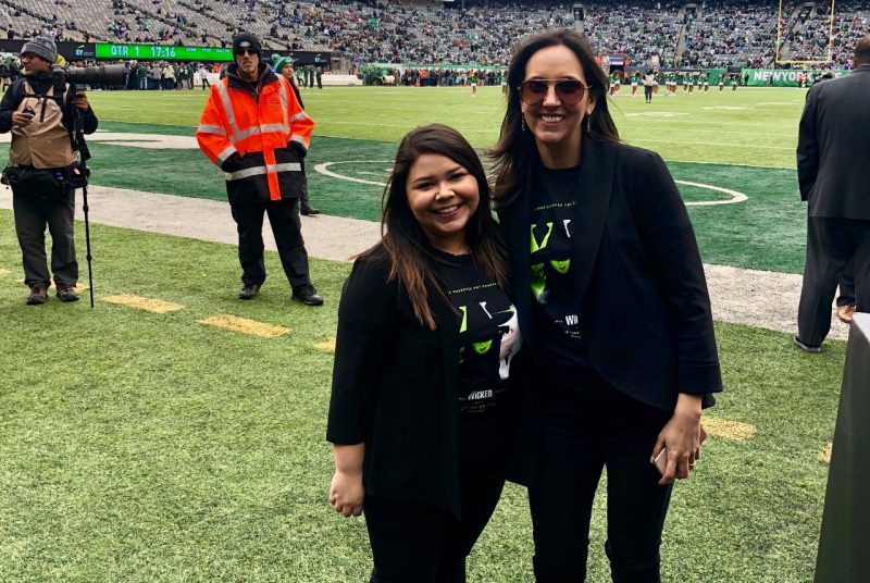 Marissa Gonzales and her coworker, both young adult females with brown hair, standing on a football field.