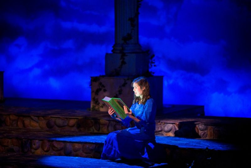 A photo of Ella in Ella Enchanted the Musical reading a magical storybook