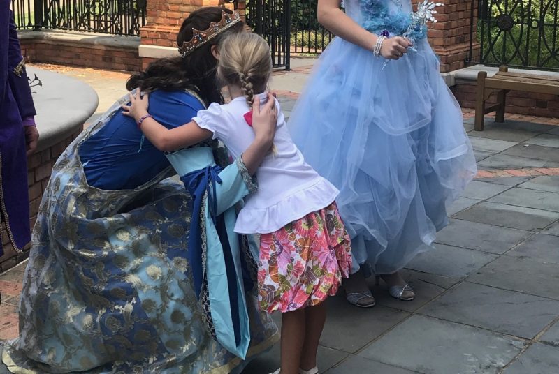 A young girl hugging Princess Ella.