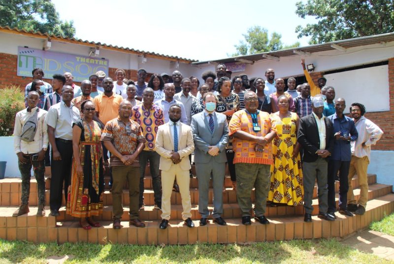 A group of people that have attend a marketing workshop in Malawi standing on a platform in front of a building outdoors.