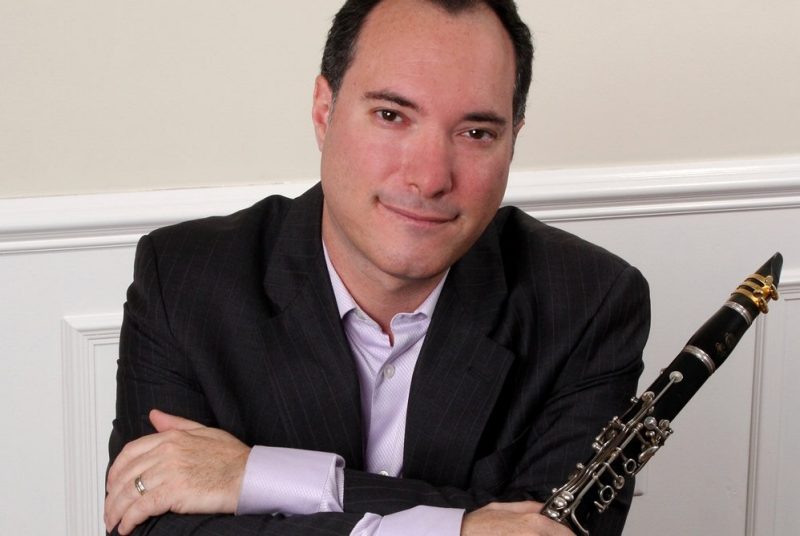 Photo of a man wearing a dark jacket, holding a clarinet