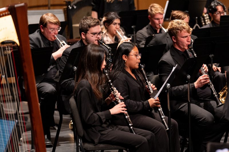 Students in an ensemble playing music together on stage.