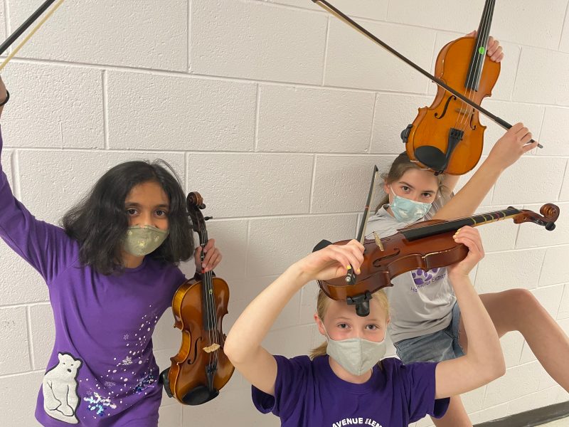 Three campers pose with their string instruments.